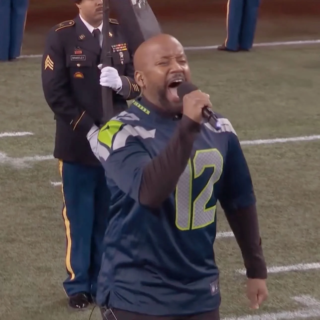 Man singing into a microphone on a football field