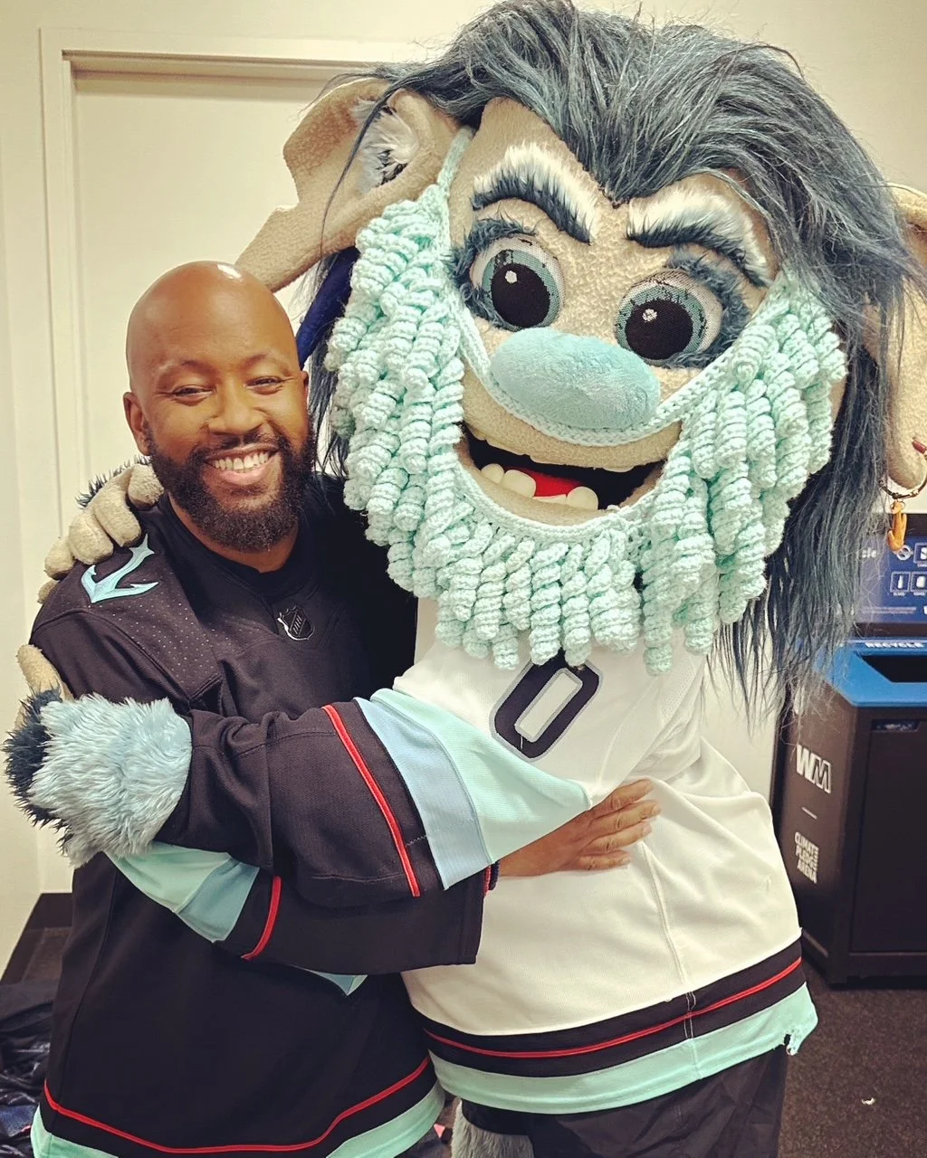 Person hugging a sports mascot in a jersey with a playful expression.