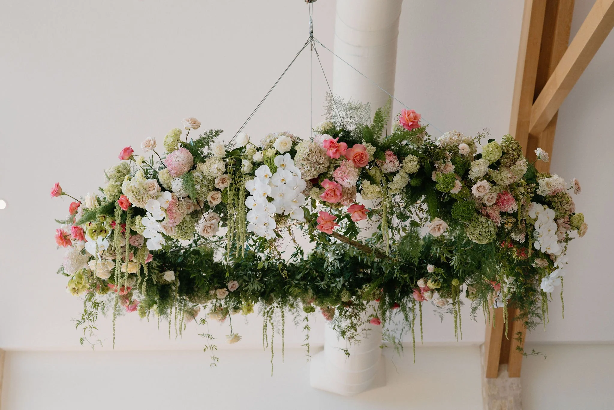 Pendant floral arrangement with pink, white, and green flowers and greenery.