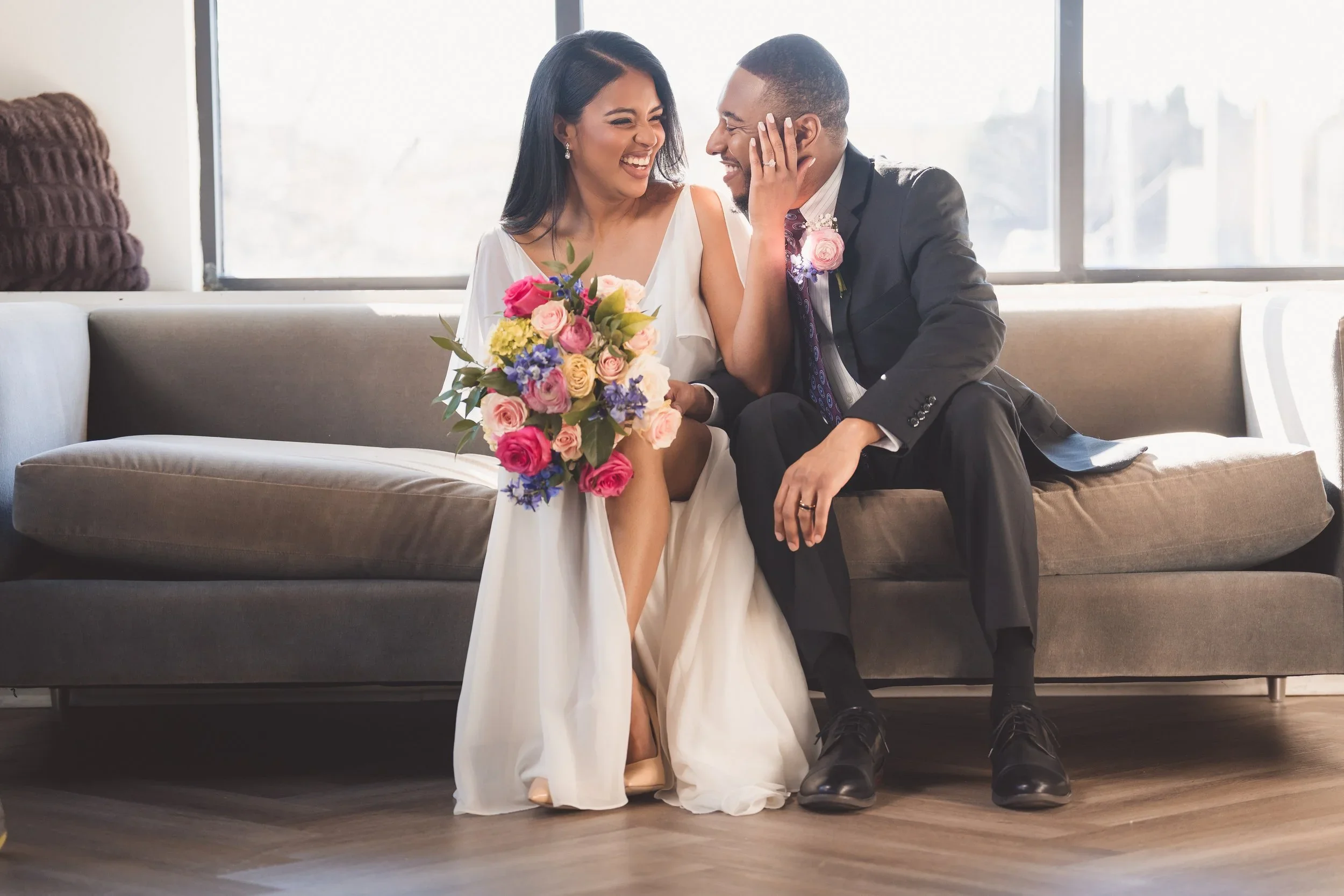 Virginia wedding couple laughing and smiling while sitting on a sofa together