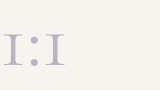A minimalist graphic with the characters 'I:I' in light gray on a white background.