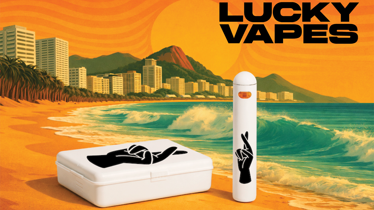 A vaping kit with a box and a vape pen featuring a hand making a peace sign, set against a beach background with city buildings and mountains, and the words 'Lucky Vapes' in bold black letters.