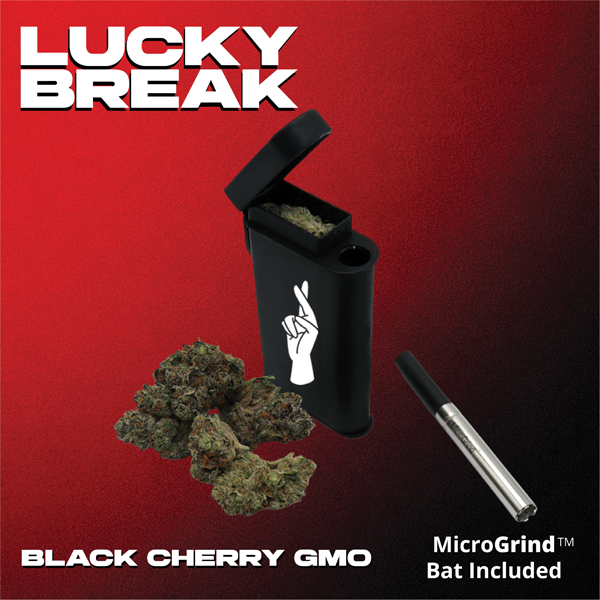 Black Cherry GMO cannabis buds with a black portable vaporizer, a glass cartridge, and a MicroGrind bat on a red and black background with white text for Lucky Break.