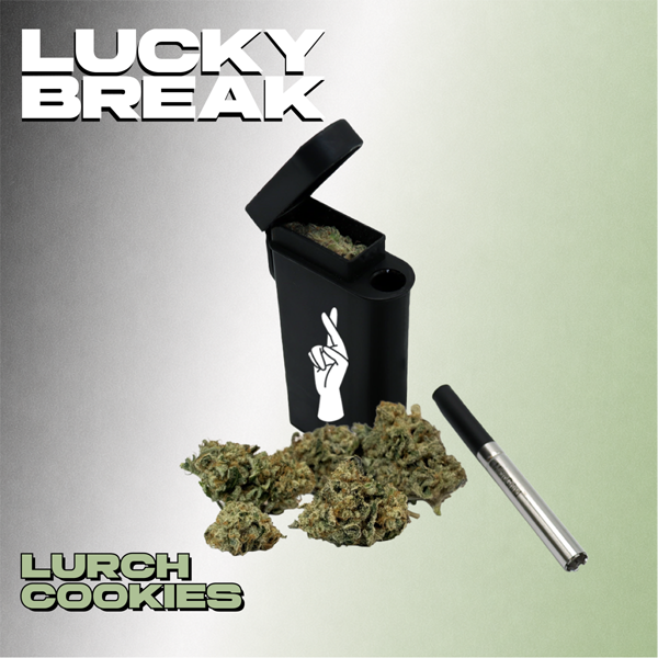 A black vape pen with a lid open, revealing cannabis inside, surrounded by cannabis buds, and a silver vape cartridge lying next to it. The background is split with a gray and green gradient. Text in the image reads 'Lucky Break' at the top and 'Lurch Cookies' at the bottom.