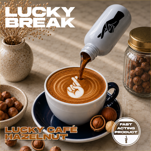 A cup of hazelnut coffee with latte art in the shape of a peace sign, being poured from a bottle with a hand making the peace sign. Surrounding items include hazelnuts, a jar of nuts, a vase with dried flowers, and a spoon, on a beige surface. Text reads "Lucky Break" and "Lucky Café Hazelnut," with a badge indicating a fast-acting product.