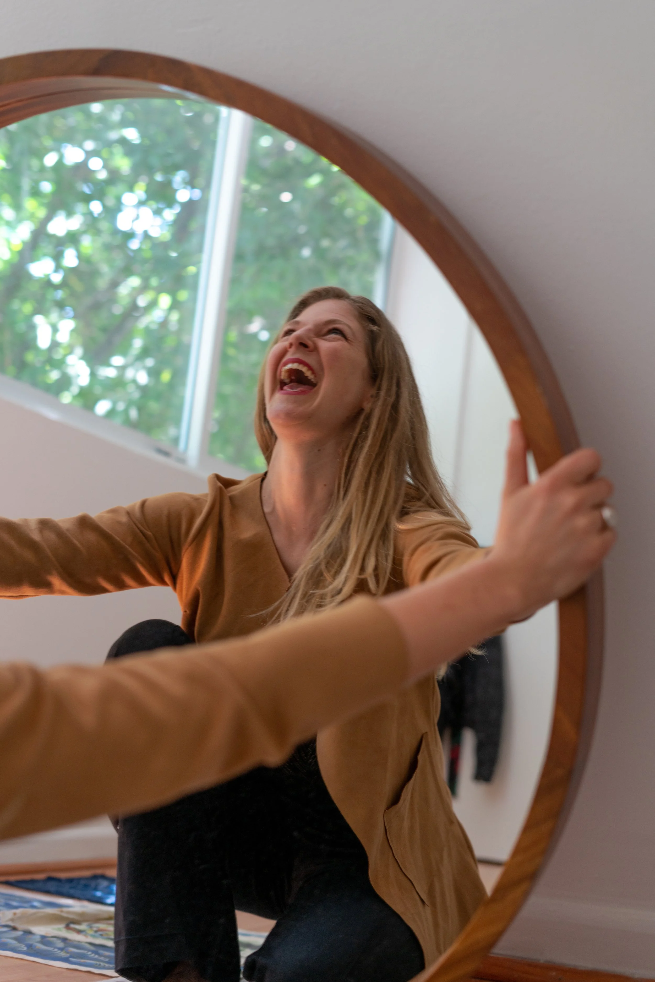 Flora Petri, female leadership coach high performers · erotic intelligence coach · somatic coach for men, laughing radiantly into mirror, golden Blazer, CDMX.