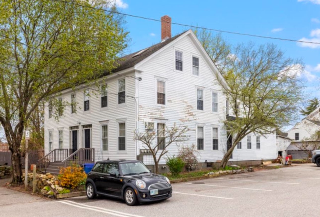 White colonial-style house with black car parked in front