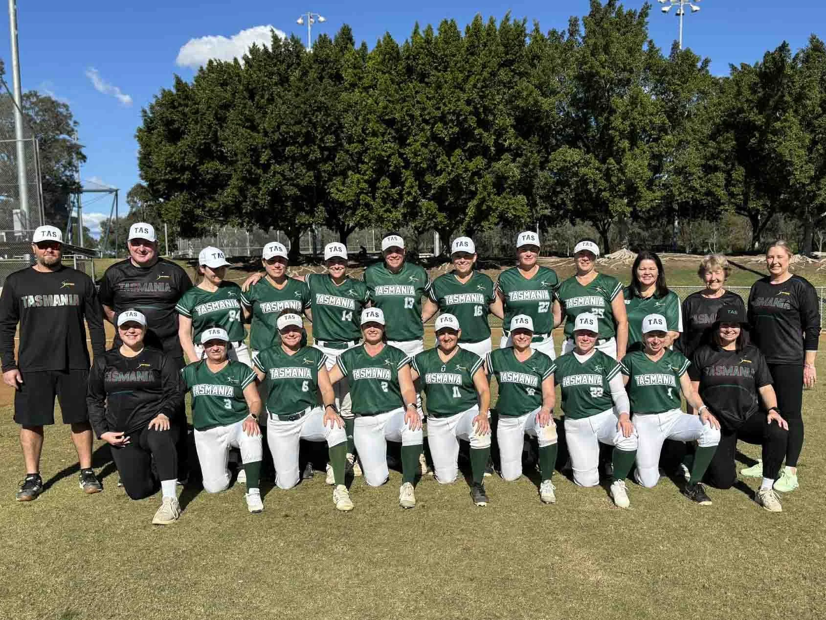 A team photo of the Tassie Thunder over 35's Women's Softball Team, in team uniforms, along with six team staff members wearing black clothing.