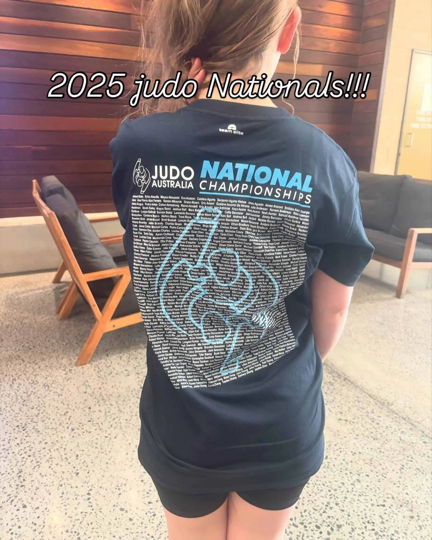 A girl with her back to the camera, wearing a Australian 2025 National Judo Championship t-shirt. 