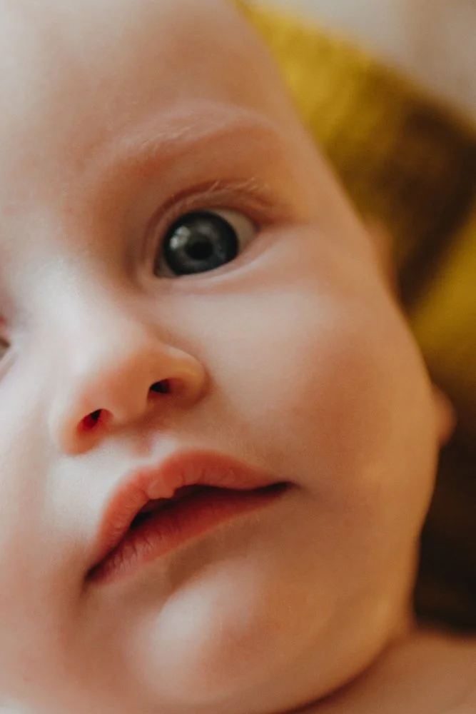 Nahaufnahme eines Babys mit blauen Augen, schließt nicht, schaut direkt in die Kamera.