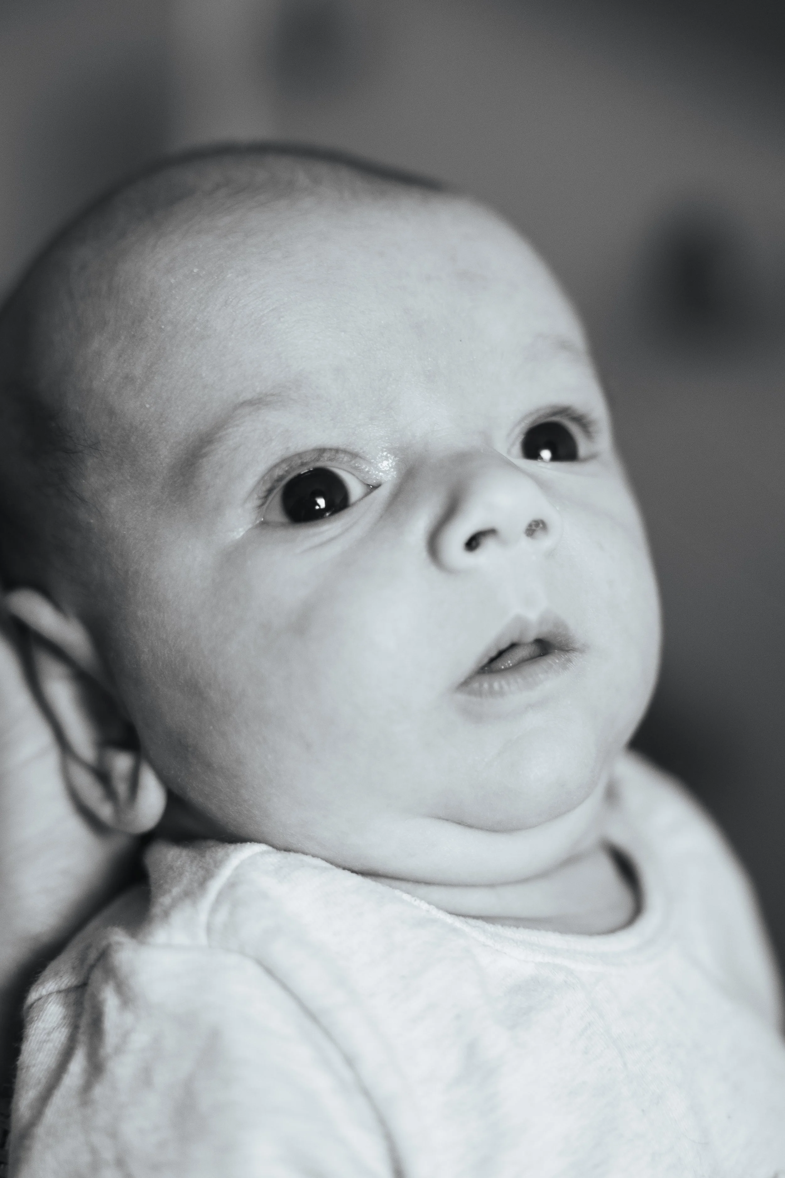 Close-up of a baby with big eyes looking slightly upward.