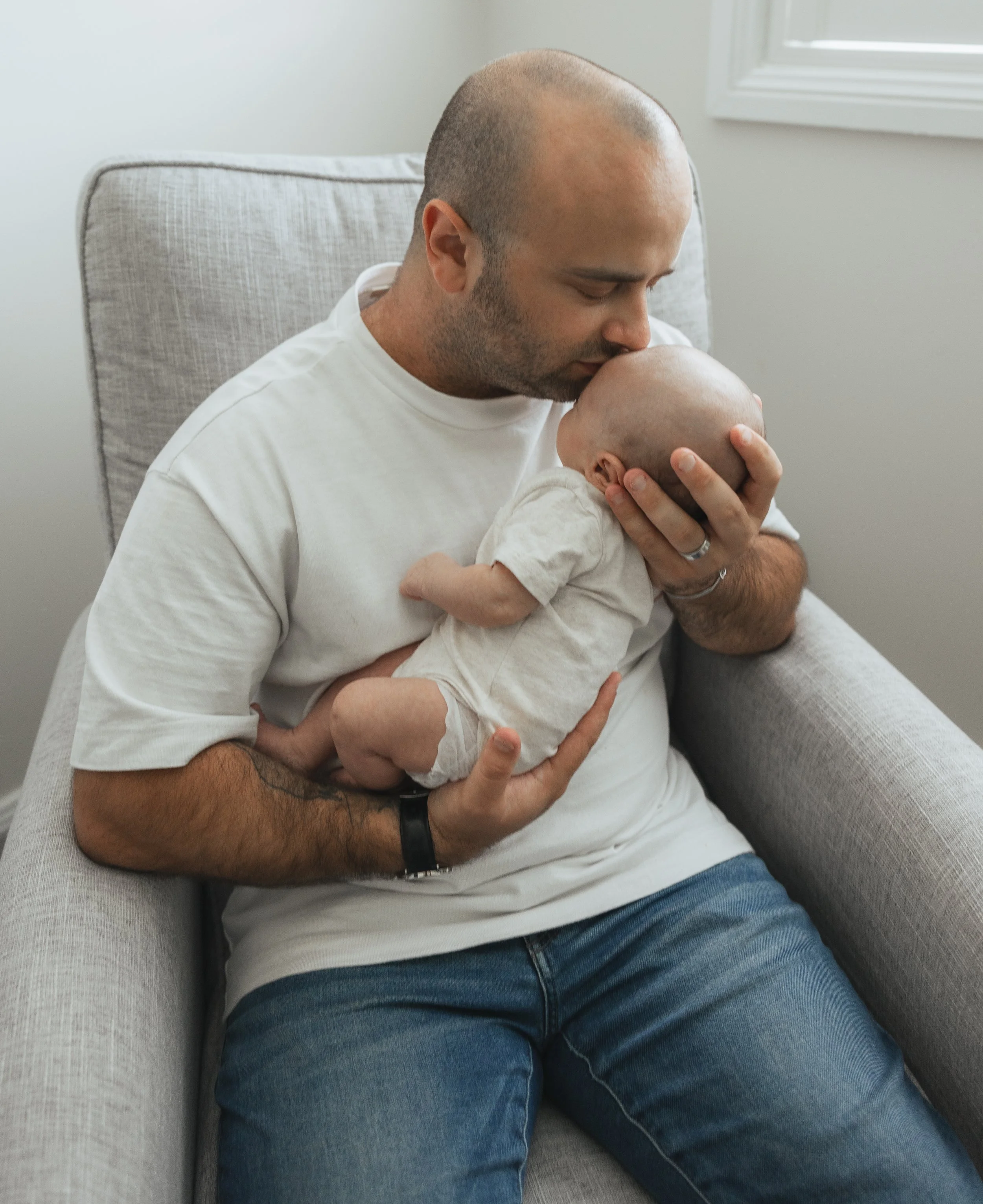 A man holding a baby close to his face in a cozy indoor setting.