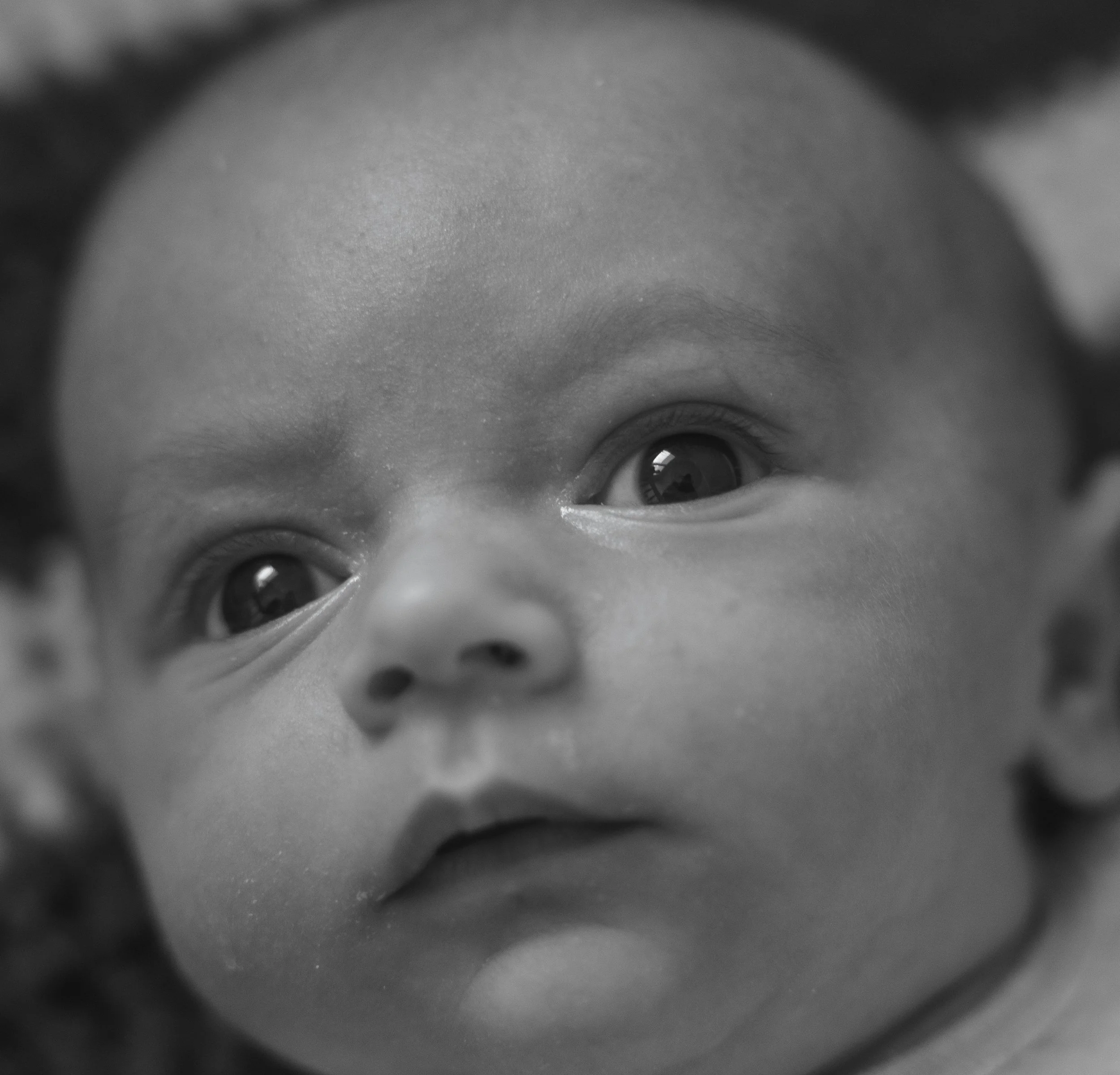 Close-up black-and-white photo of a baby's face, focusing on the eyes and nose.