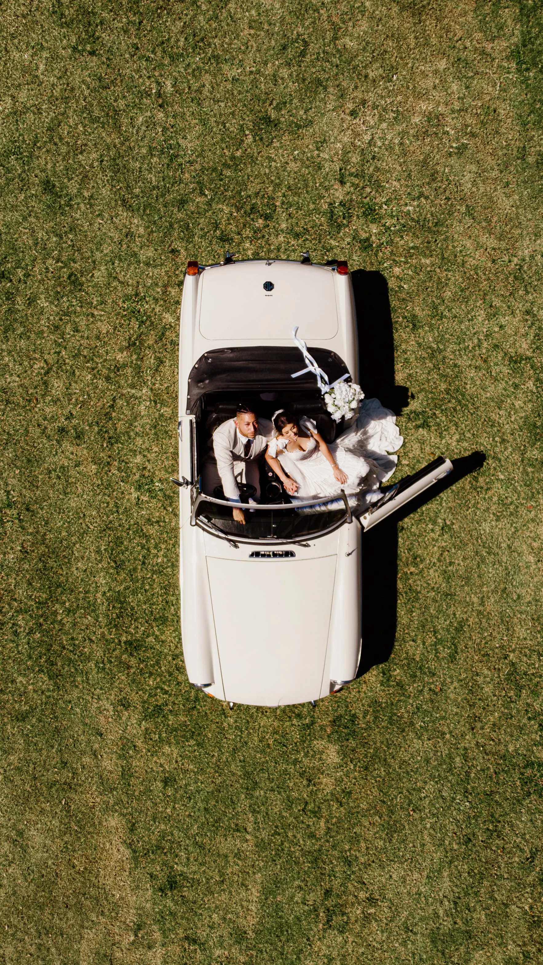 drone shot of a vintage car with newlyweds looking up