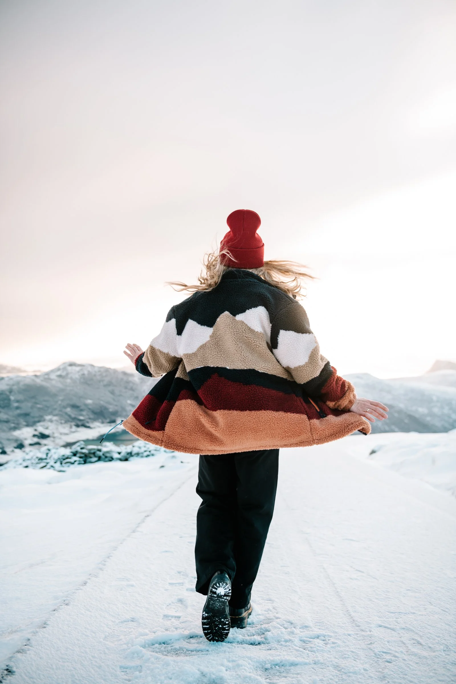 model wearing teddy jacket and beanie dancing on a snowy road