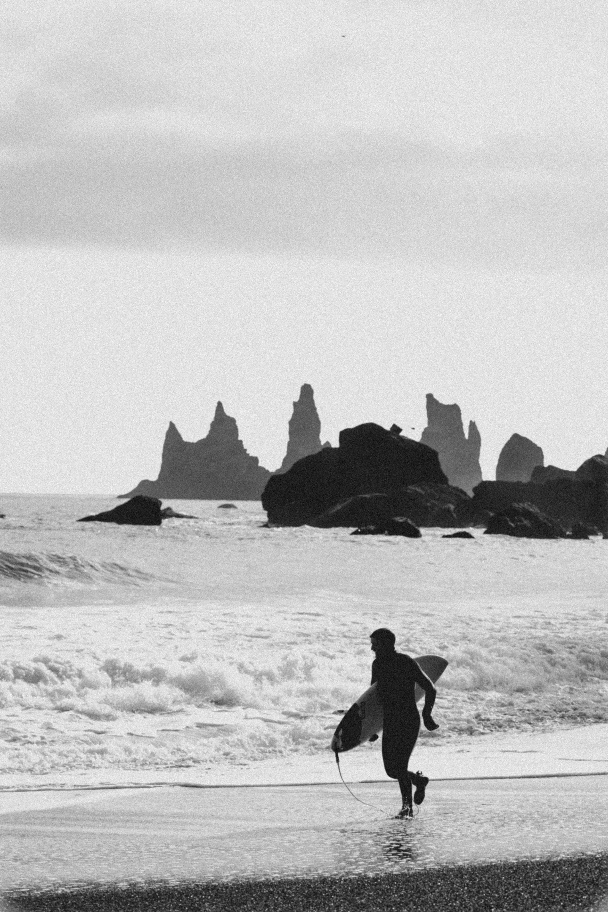surfer in wetsuit running on beach