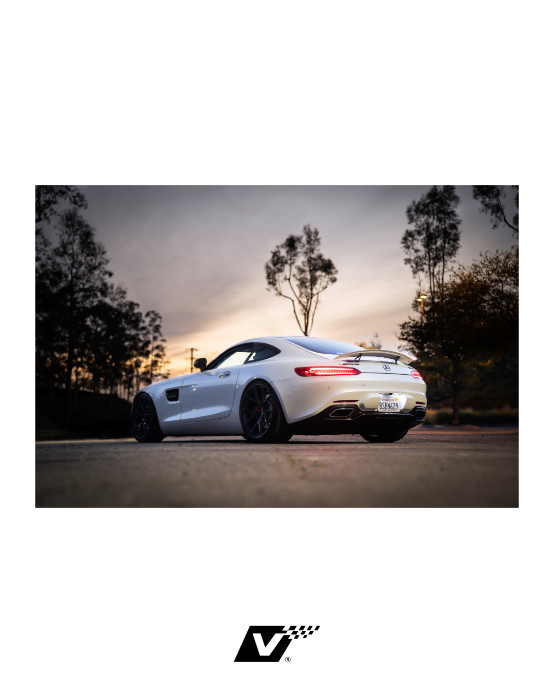 Rear view of a white sports car parked outdoors during sunset with trees in the background.