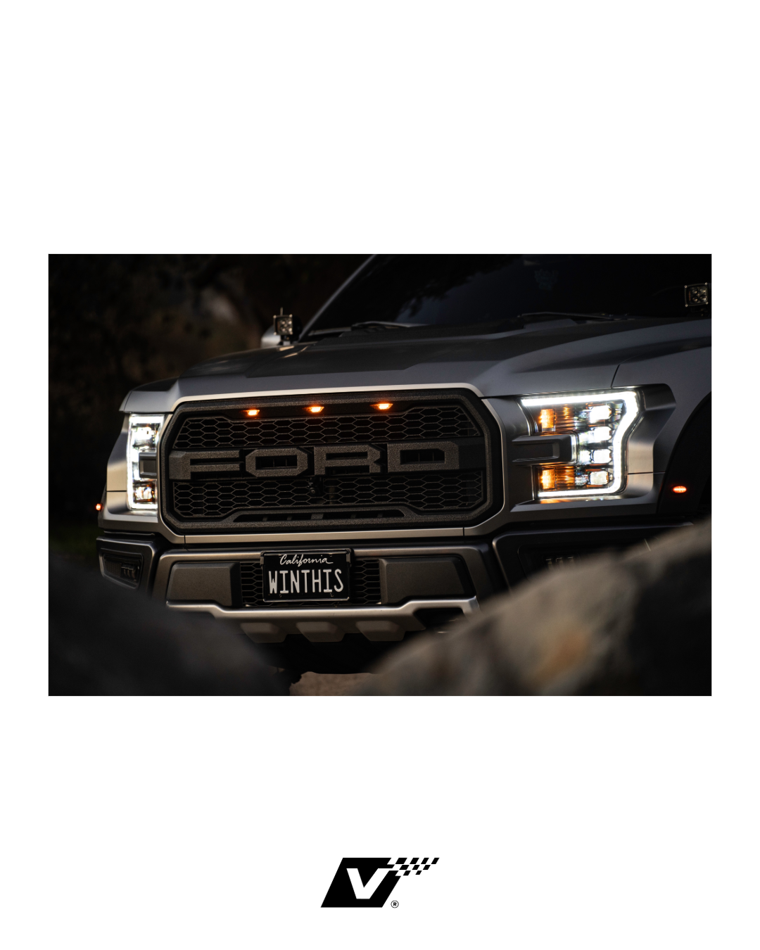 Front view of a Ford vehicle with illuminated headlights and a custom California license plate reading 'WINTHIS' in a dark setting.