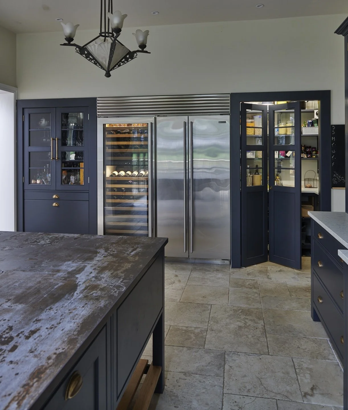 Kitchen with dark blue cabinets, a marble-topped island, and a stainless steel double-door wine refrigerator.