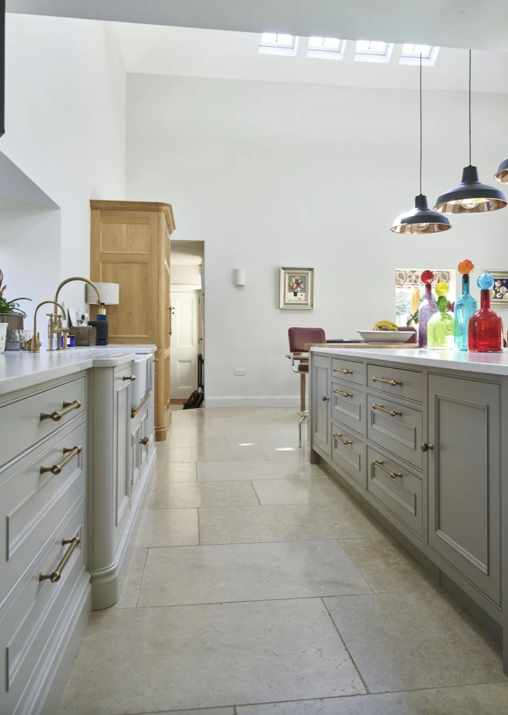 Bright kitchen with white cabinetry, a kitchen island with colorful bottles, and a skylight letting in natural light.