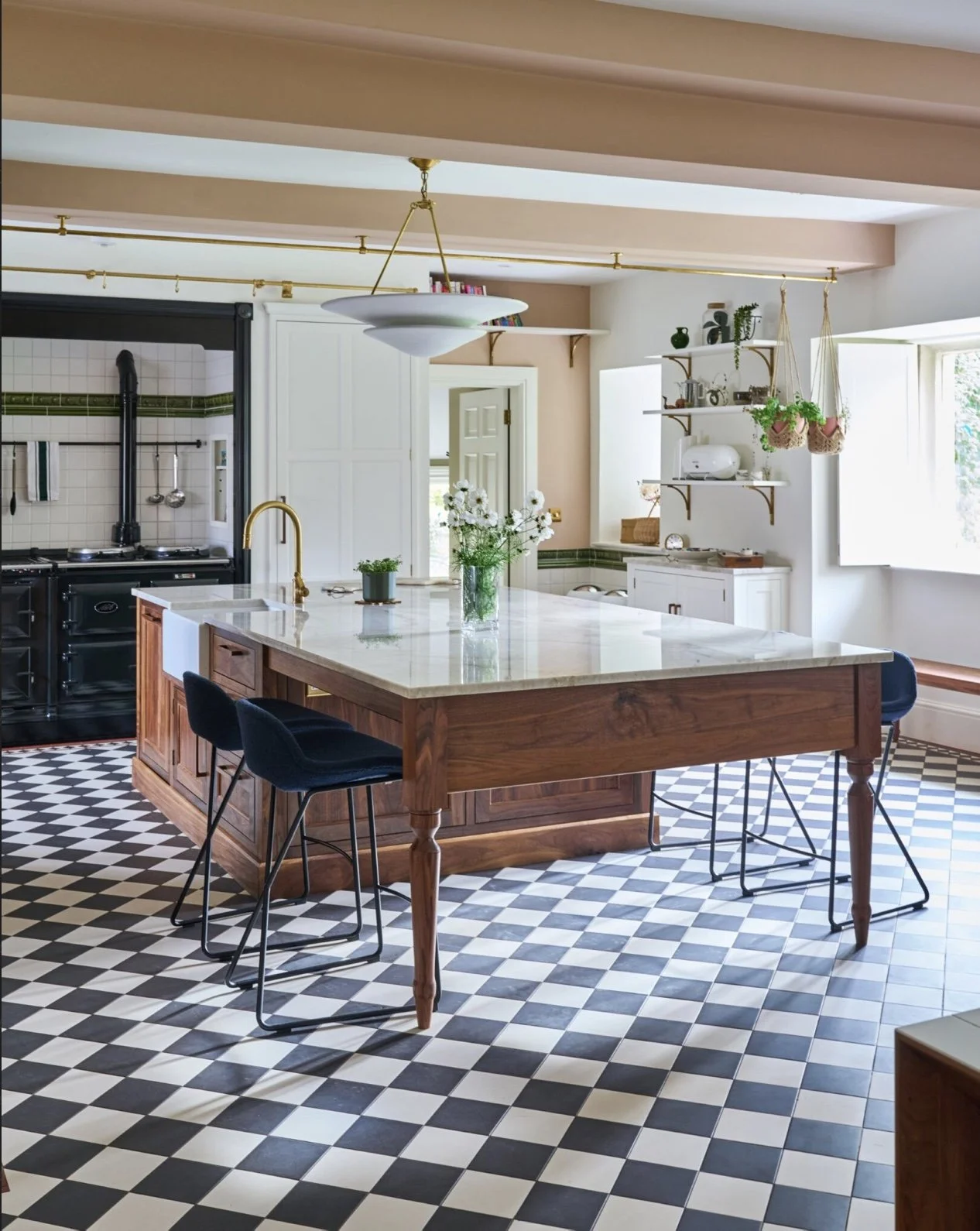 Bright kitchen with a large wooden island and black-and-white checkered floor, white cabinetry, and open shelves with plants and kitchenware.