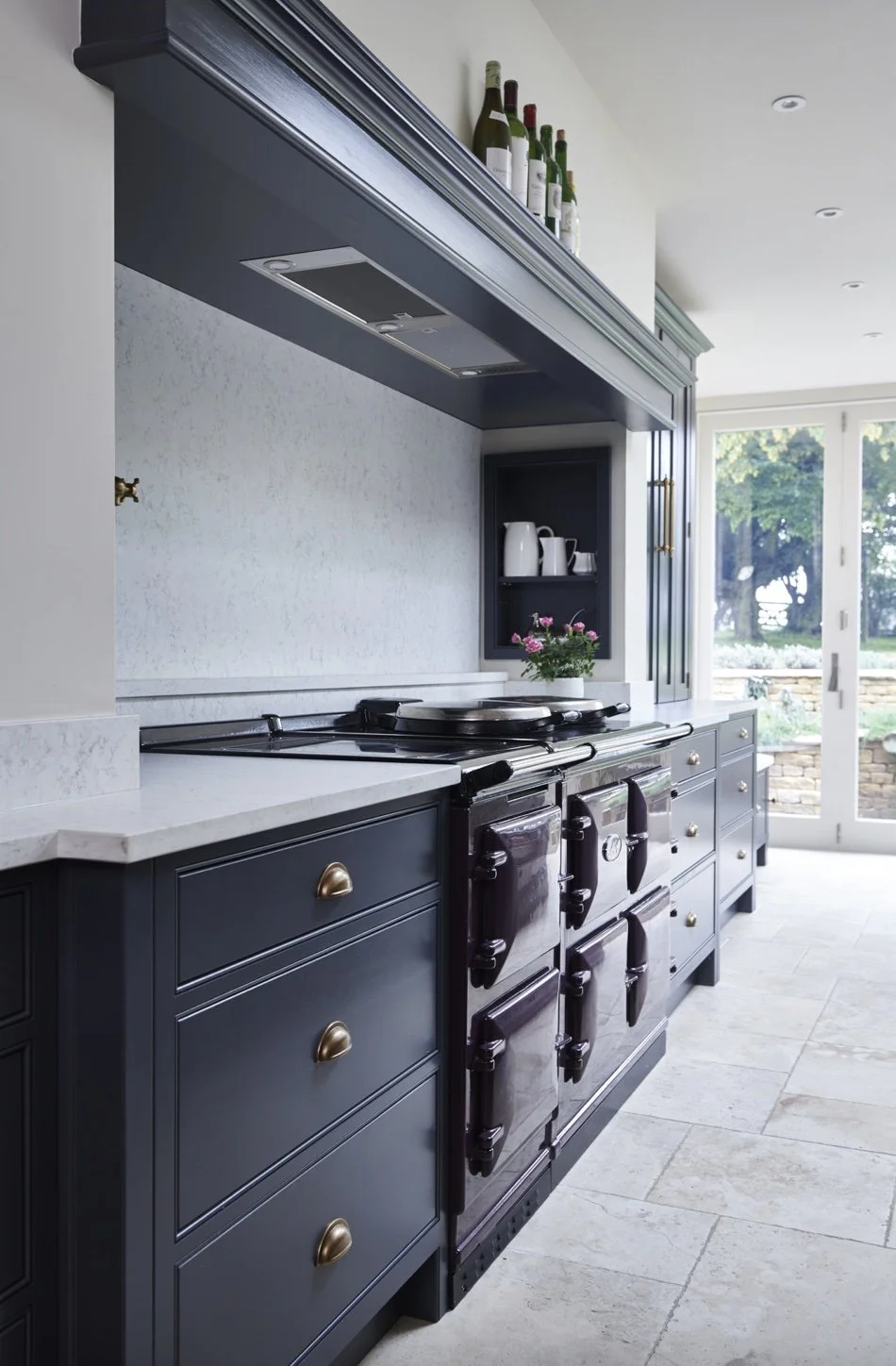 Kitchen with navy blue cabinets, white countertops, a stove with two ovens, and a sliding glass door leading outside.