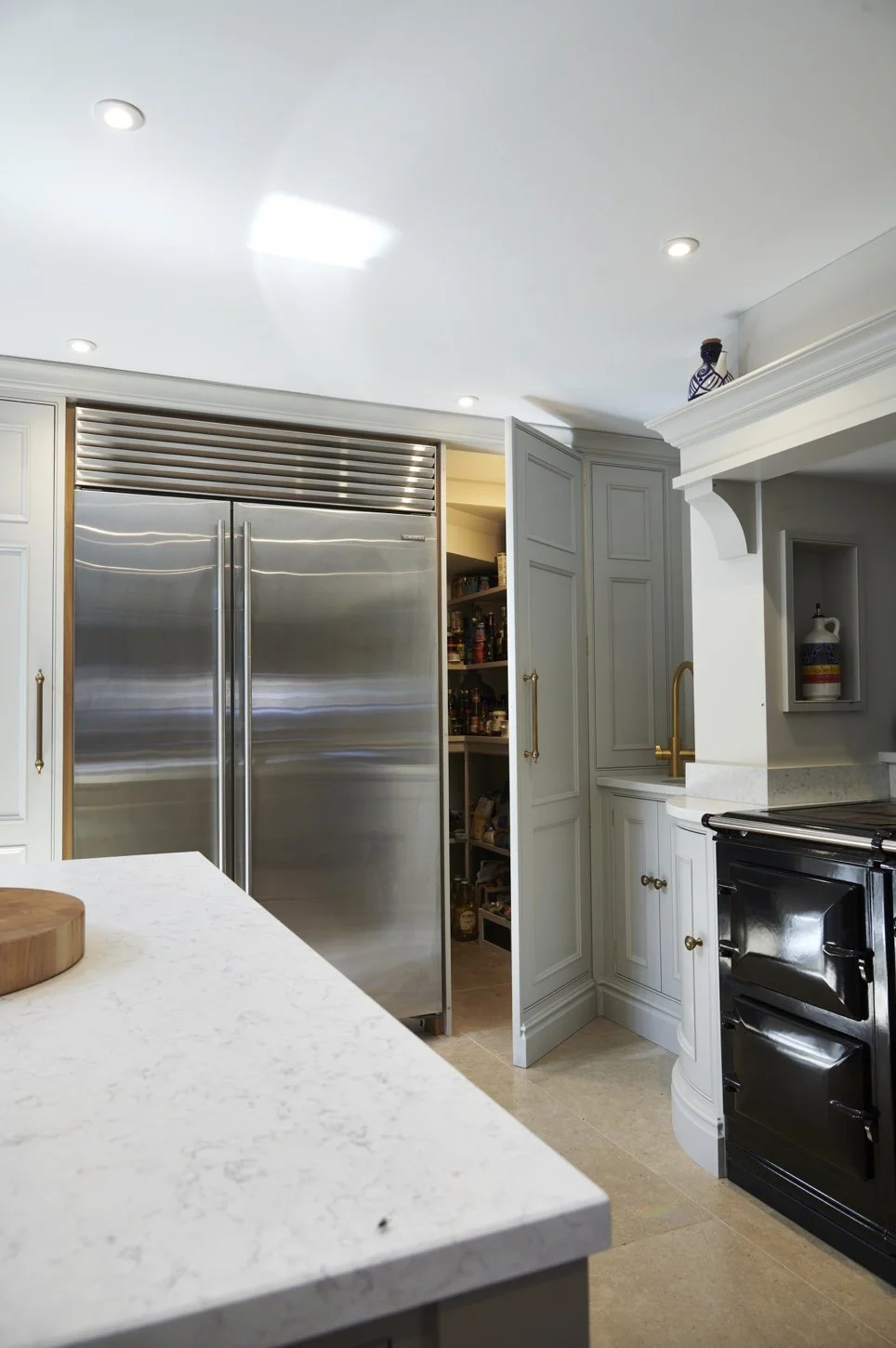 Kitchen with white cabinets, a black stove, a metal double-door refrigerator, and open pantry shelves filled with jars and cans.