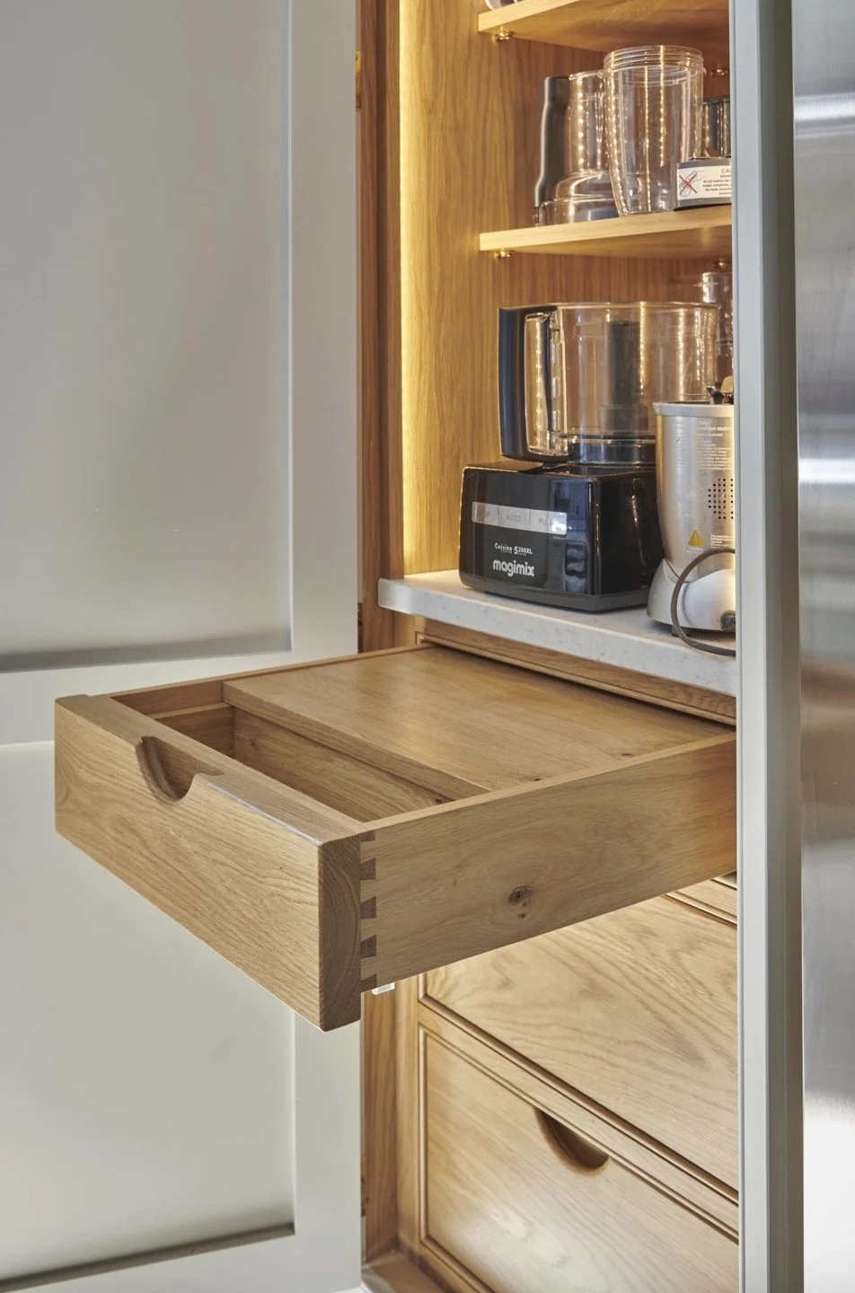 Open wooden kitchen cabinet drawer with a slide-out tray below a coffee maker and blender.