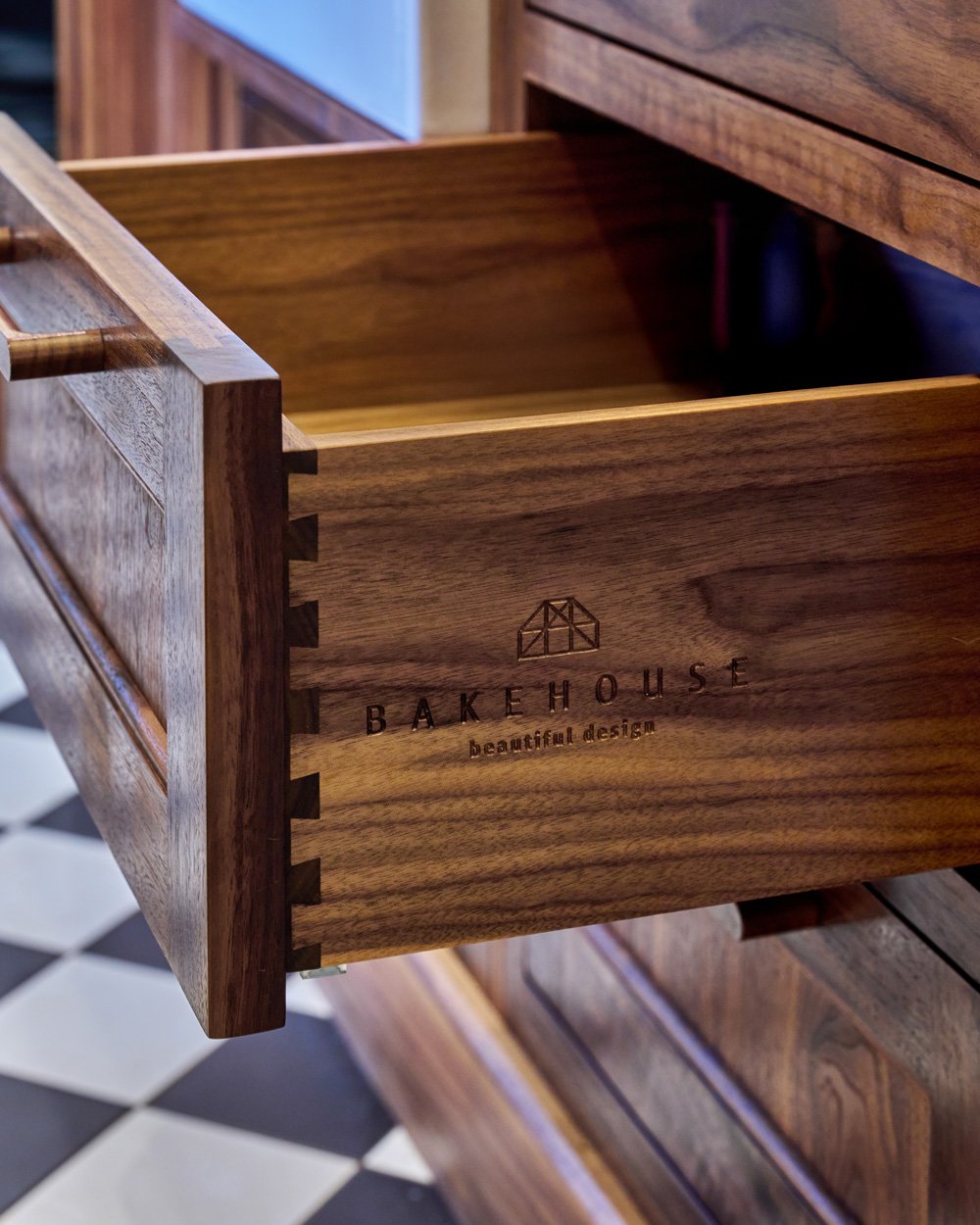 Open wooden drawer with 'Bakehouse beautiful design' logo and text, showing detailed wood craftsmanship.