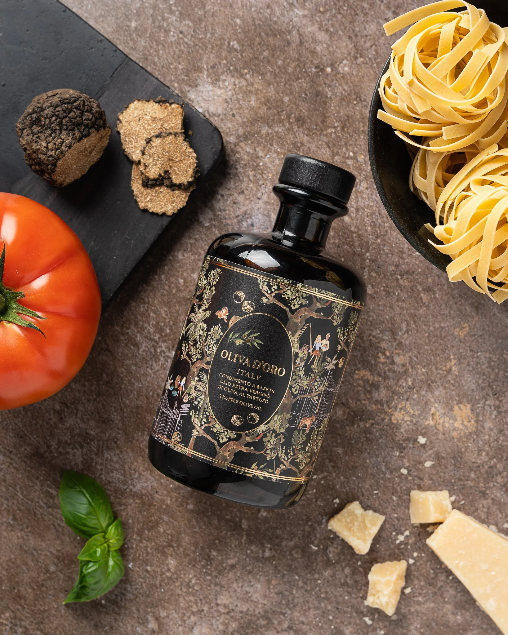 Donkere fles olijfolie, rijen pasta in een pan, een tomaat, basilicobladeren en stukjes Parmezaanse kaas op een houten ondergrond.