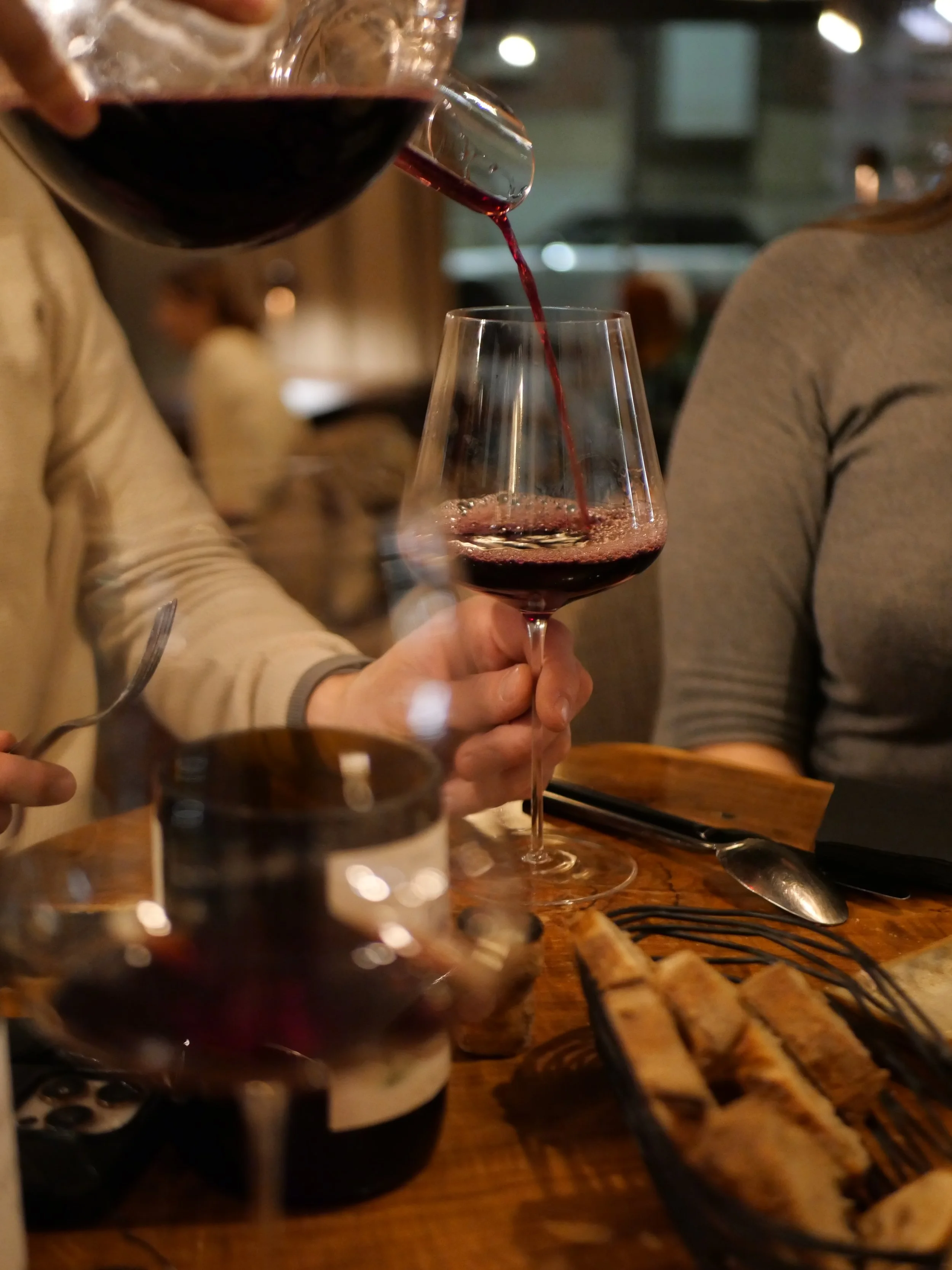 Un vin rouge d'exception est servi d'une carafe dans une verre.