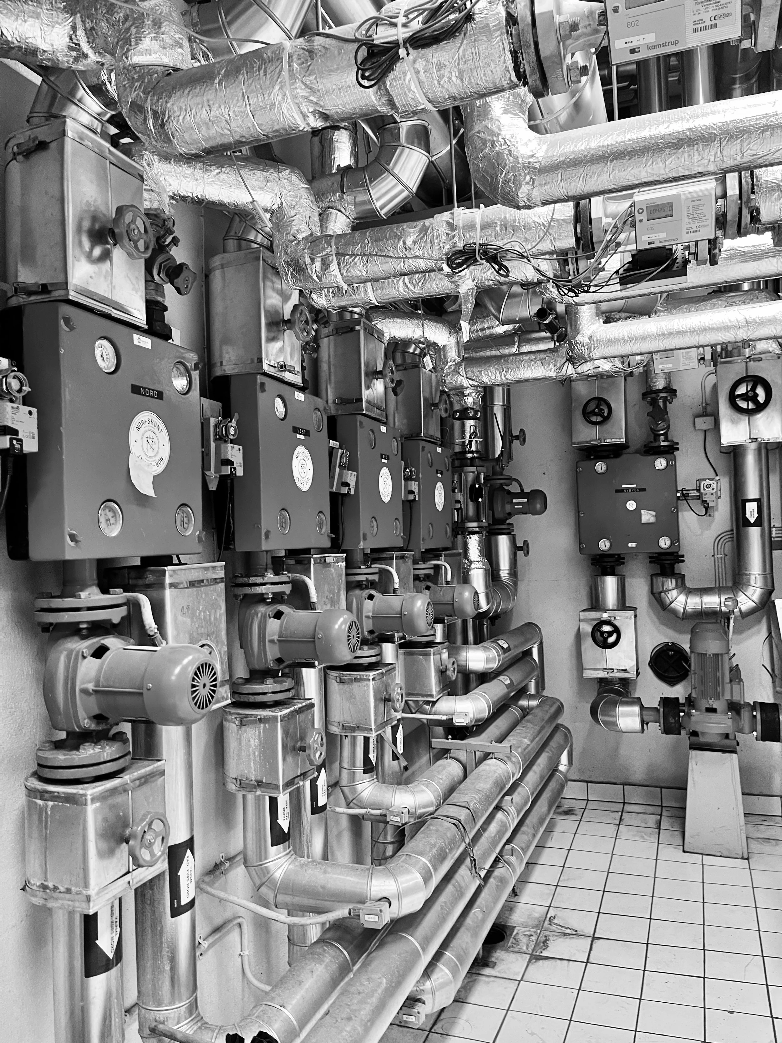 En person holder en klimaanlegg fjernkontroll rett under en veggmontert klimaanlegg.