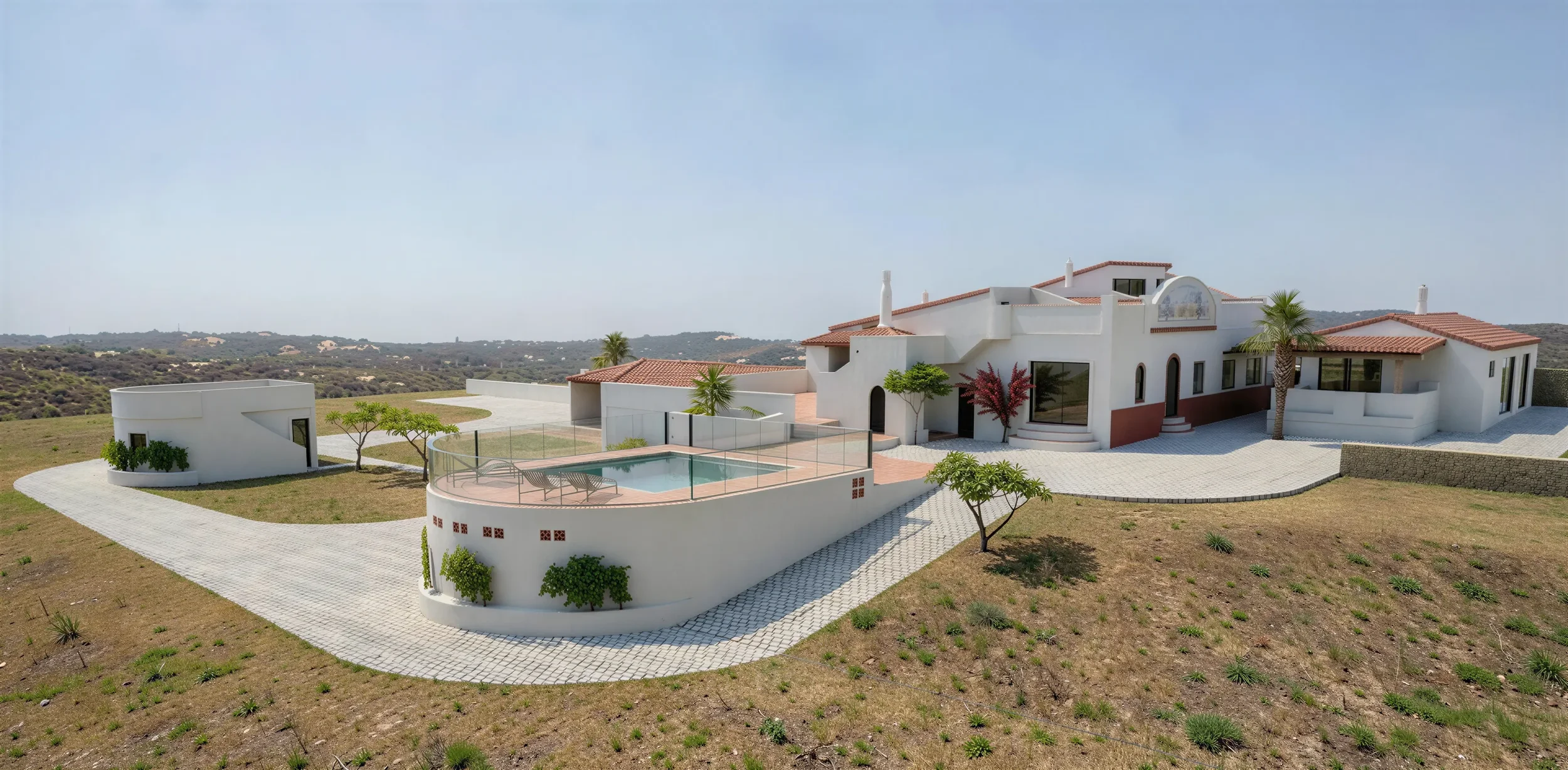 Maison moderne blanche avec piscine, entourée de paysage rural et de collines, sous un ciel clair.