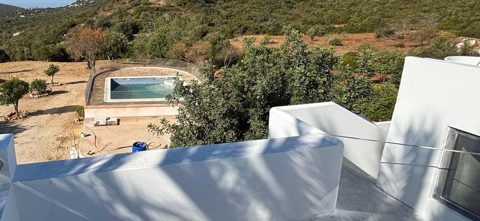 Vue d'une terrasse avec un espace jacuzzi extérieur entouré d'arbres et de nature, avec un paysage vallonné en arrière-plan