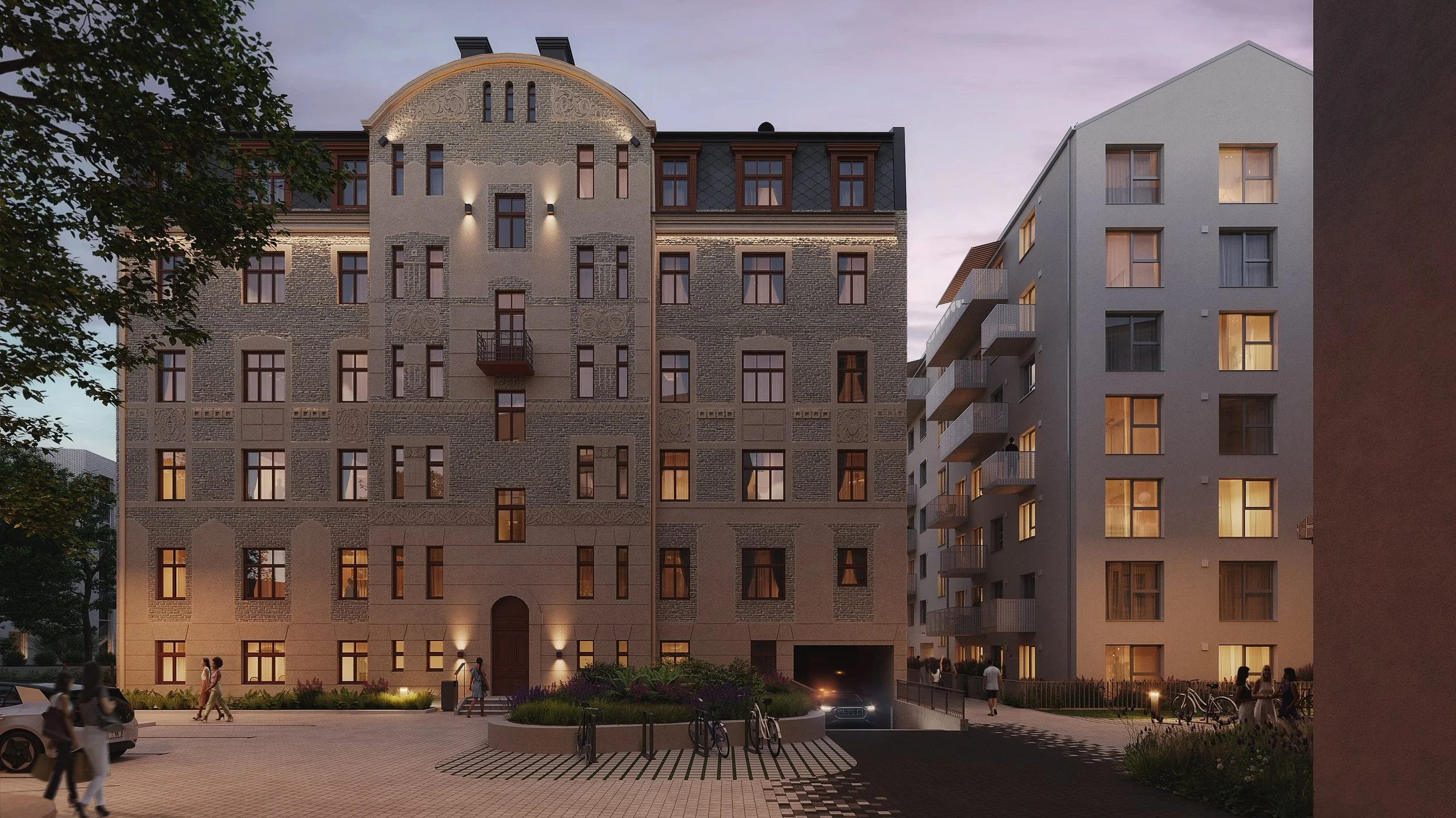 Nighttime view of modern apartment building with lit windows, balconies, and a small landscaped courtyard with people walking, bicycles, and a car parked outside.