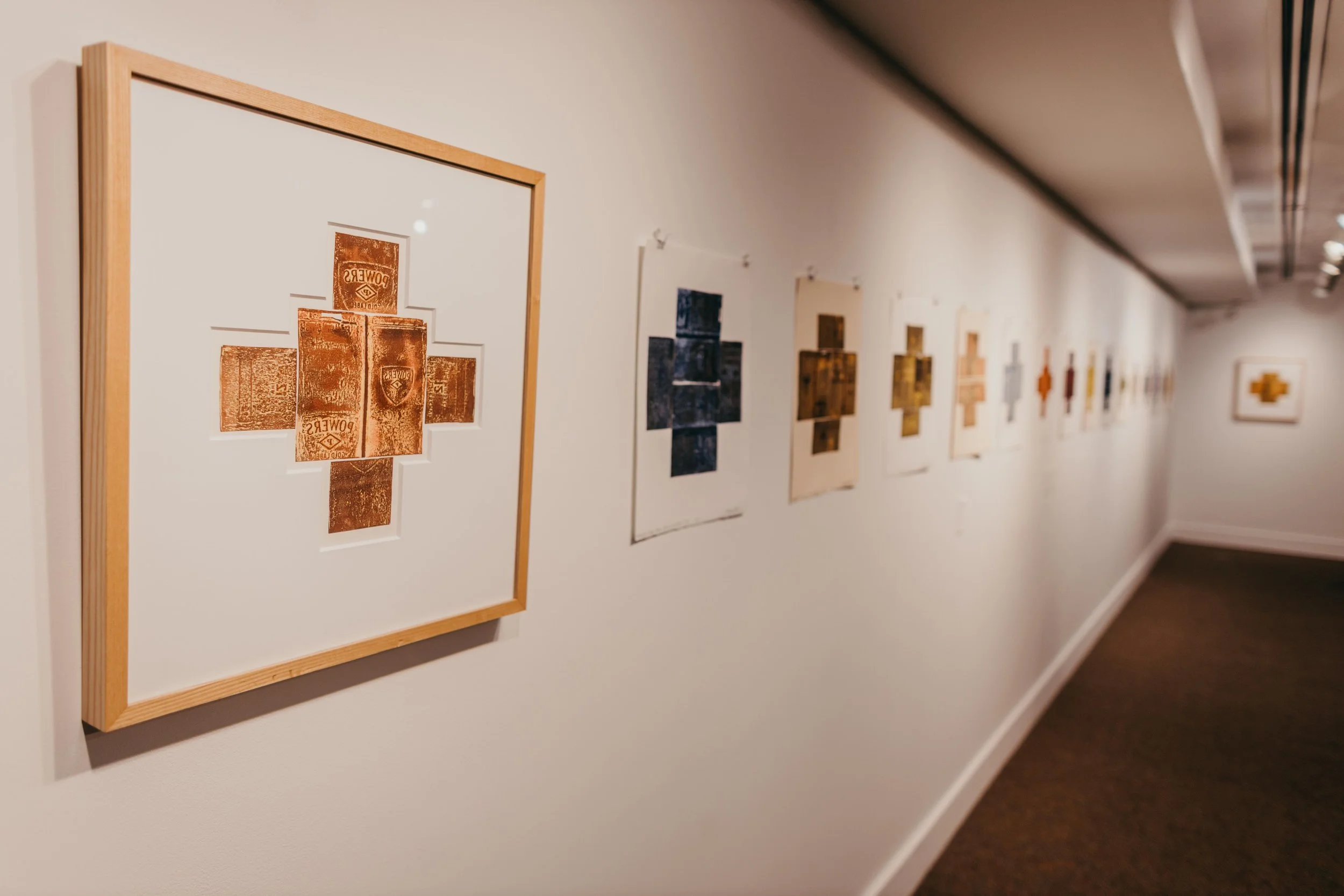Art gallery wall with framed artworks, featuring collage and print art pieces arranged in a line.