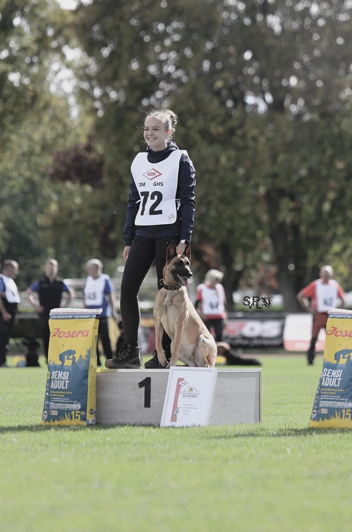 Hundetrainerin Vivienne von ViBaDog mit ihrem Malinois auf dem Siegerpodest eines Hundesport-Wettkampfs.