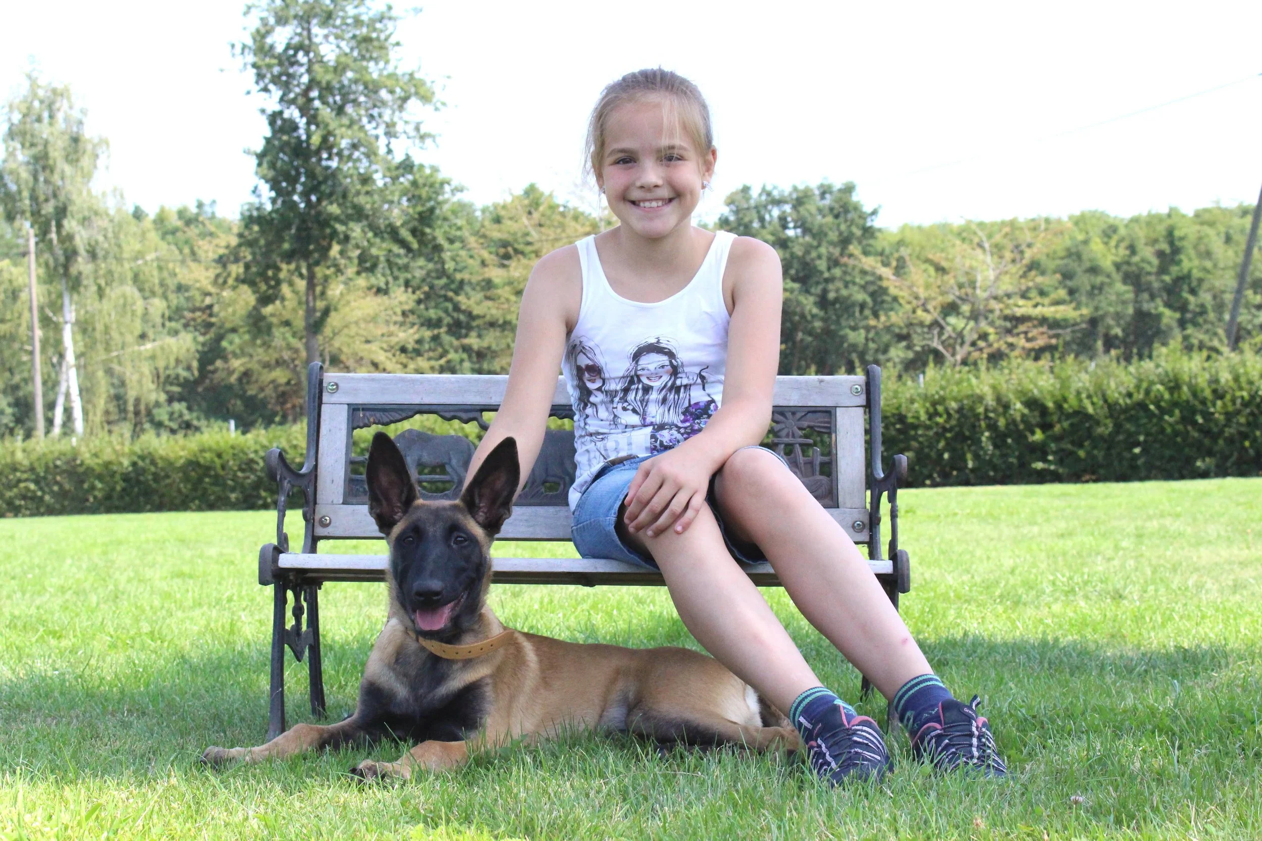 Vivienne von ViBaDog als Kind mit einem jungen Malinois auf einer Wiese – der Beginn ihrer Leidenschaft für Hunde und Hundetraining.