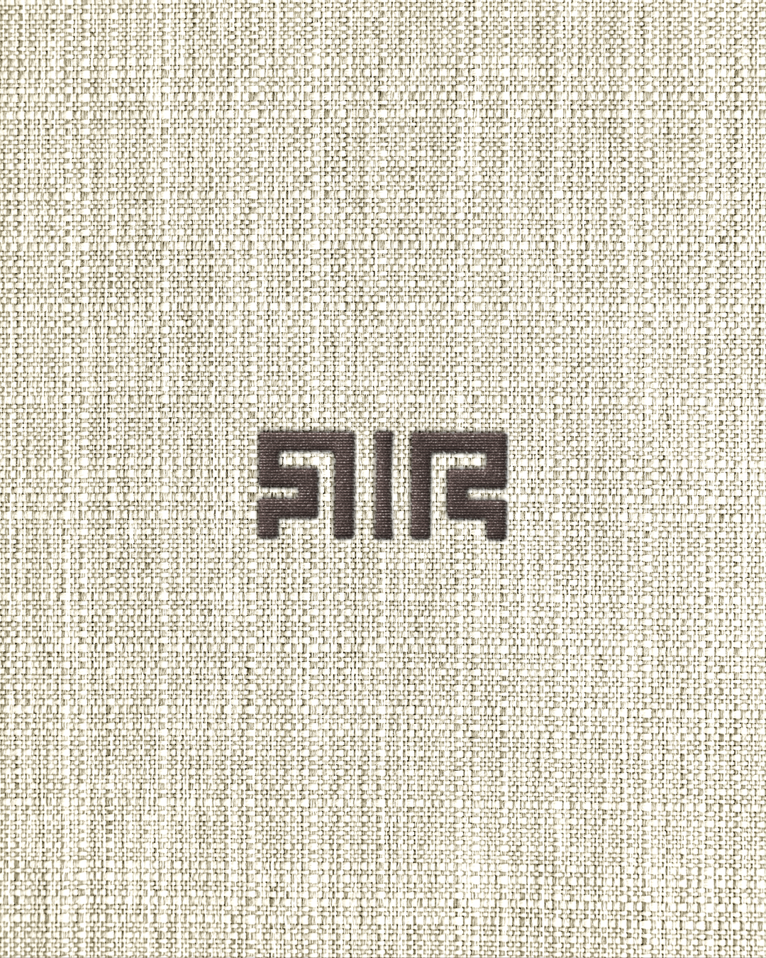 Embroidered Richē brand symbol inspired by traditional Kuba textile patterns from the Democratic Republic of Congo, stitched onto textured natural fabric.
