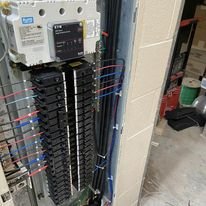 Electrical circuit breaker panel with wired connections inside a utility closet.