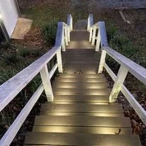 Night view of illuminated outdoor staircase with white railing.