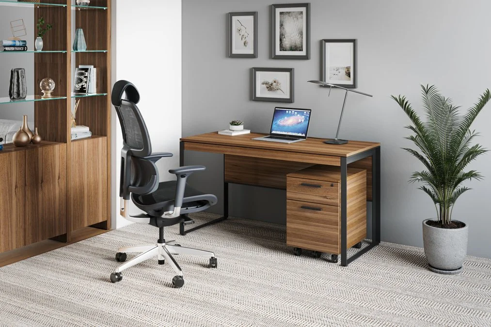 Lifestyle office view with Linea Desk and pedestal in walnut finish, ergonomic chair, and decor