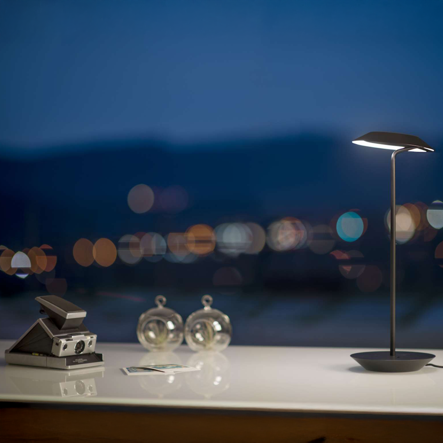Koncept Royyo Desk Light glowing on desk at night with city view