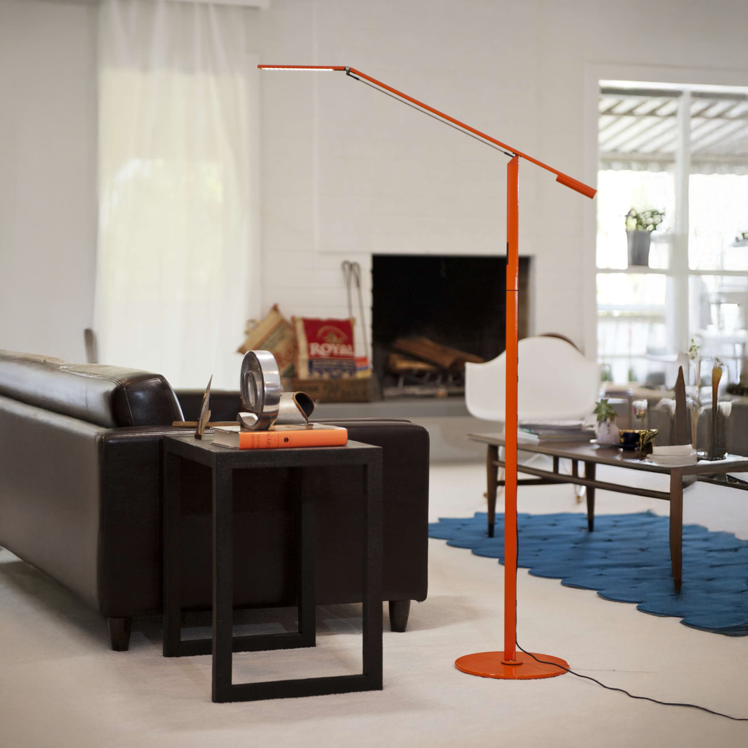 Equo Floor Lamp in orange, placed beside a modern living room sofa