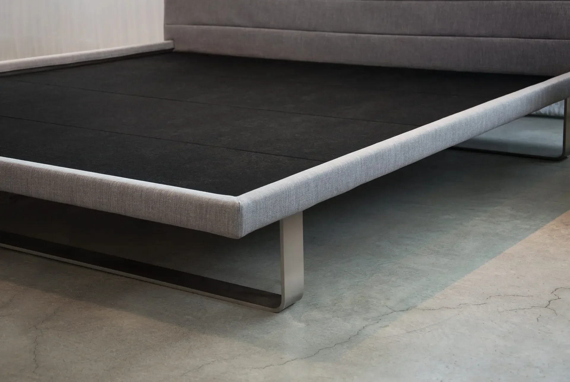 Close-up of Trica Envy Bed grey upholstered frame and metal legs