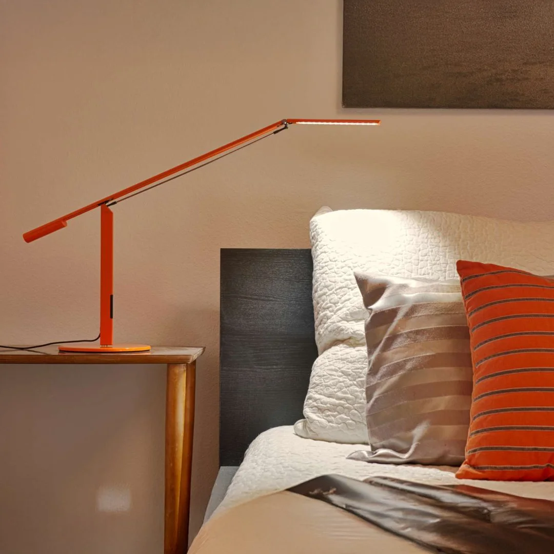 Equo Desk Lamp by Koncept in orange finish placed on a bedroom nightstand, minimalist lighting design