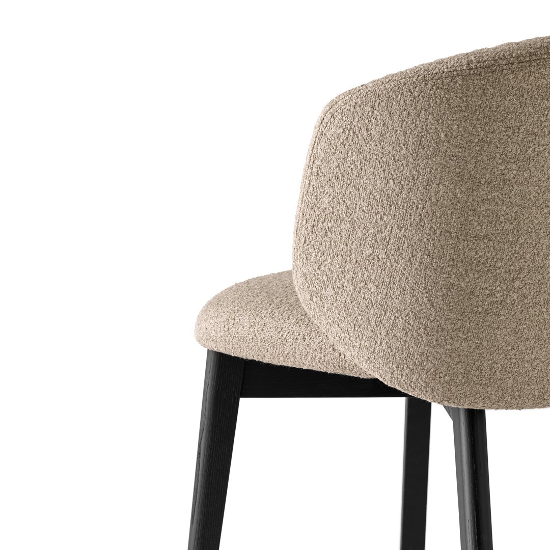 Close-up side view of Anime Dining Chair in beige textured upholstery with black legs