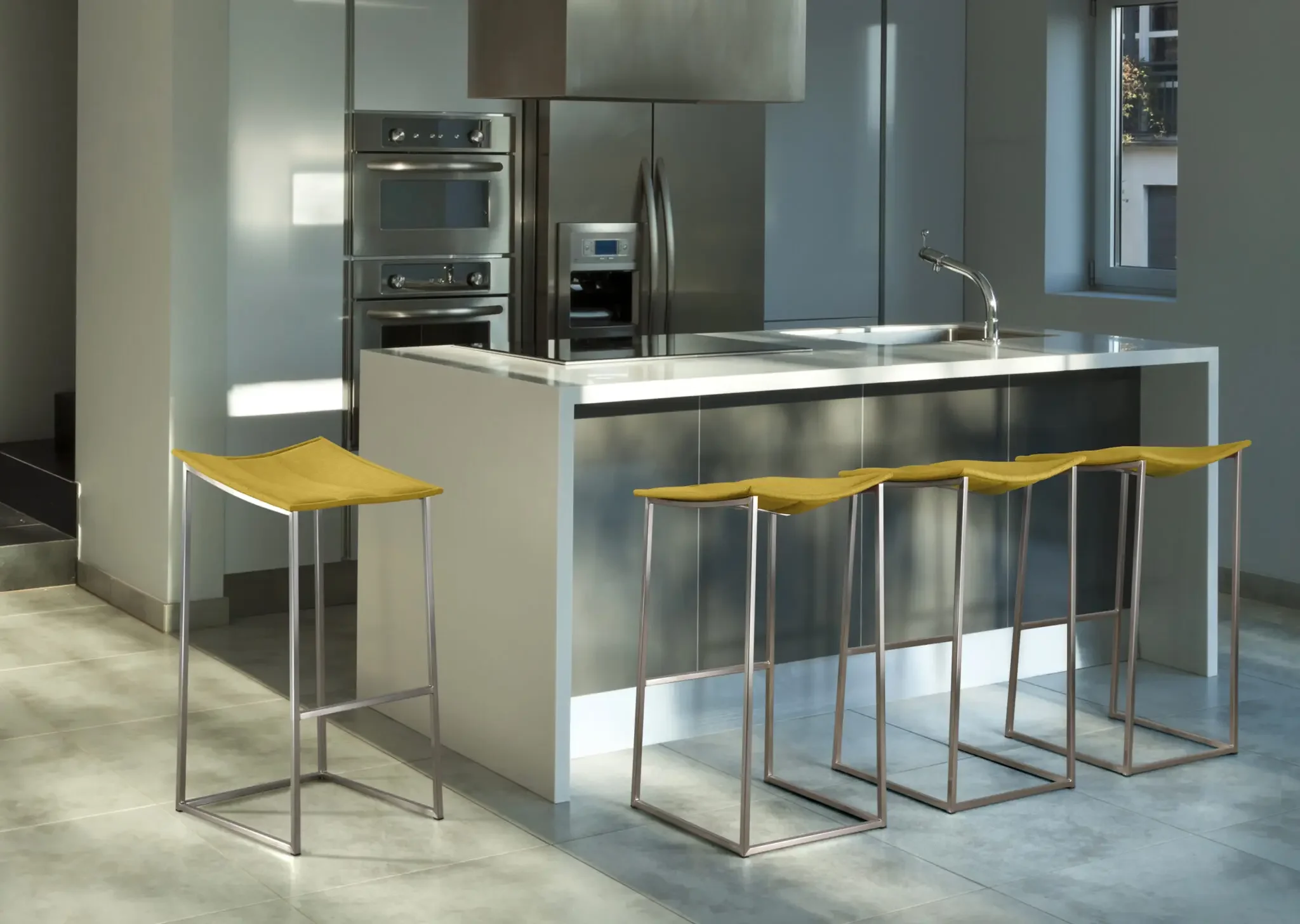 Modern kitchen with three Trica Bocca Counter Stools featuring yellow upholstered seats and stainless steel frames