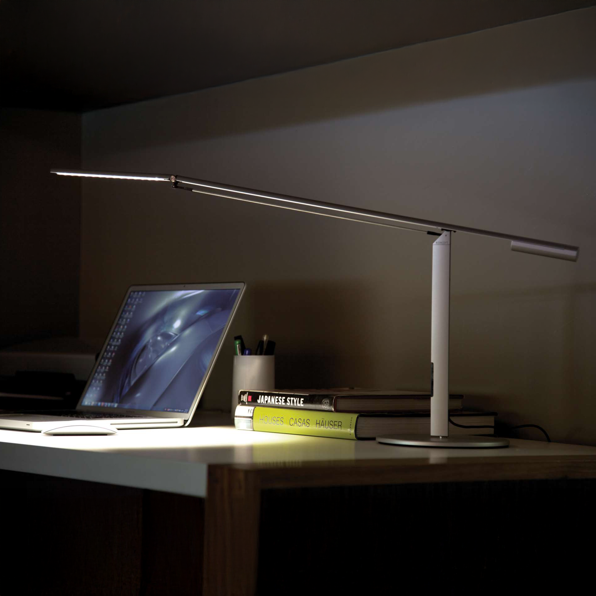 Koncept Equo Desk Lamp in silver finish on office desk beside a laptop, LED task lighting for workspace