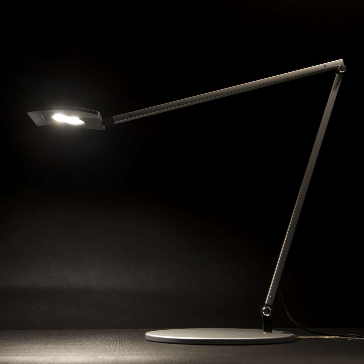 Mosso Pro adjustable LED task light in matte black, illuminated on dark background